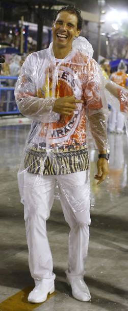 La pioggia su Rio non ha impedito a Rafa Nadal di sfilare insieme a Guga Kuerten e David Ferrer nella parata d&#39;apertura del Carnevale. E nonostante l&#39;impermeabilino di plastica... il maiorchino sfoggiava un sorriso a piena bocca...